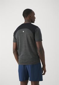 Black and gray athletic t-shirt with short sleeves, featuring a round neckline and a subtle logo on the back. Paired with blue shorts.