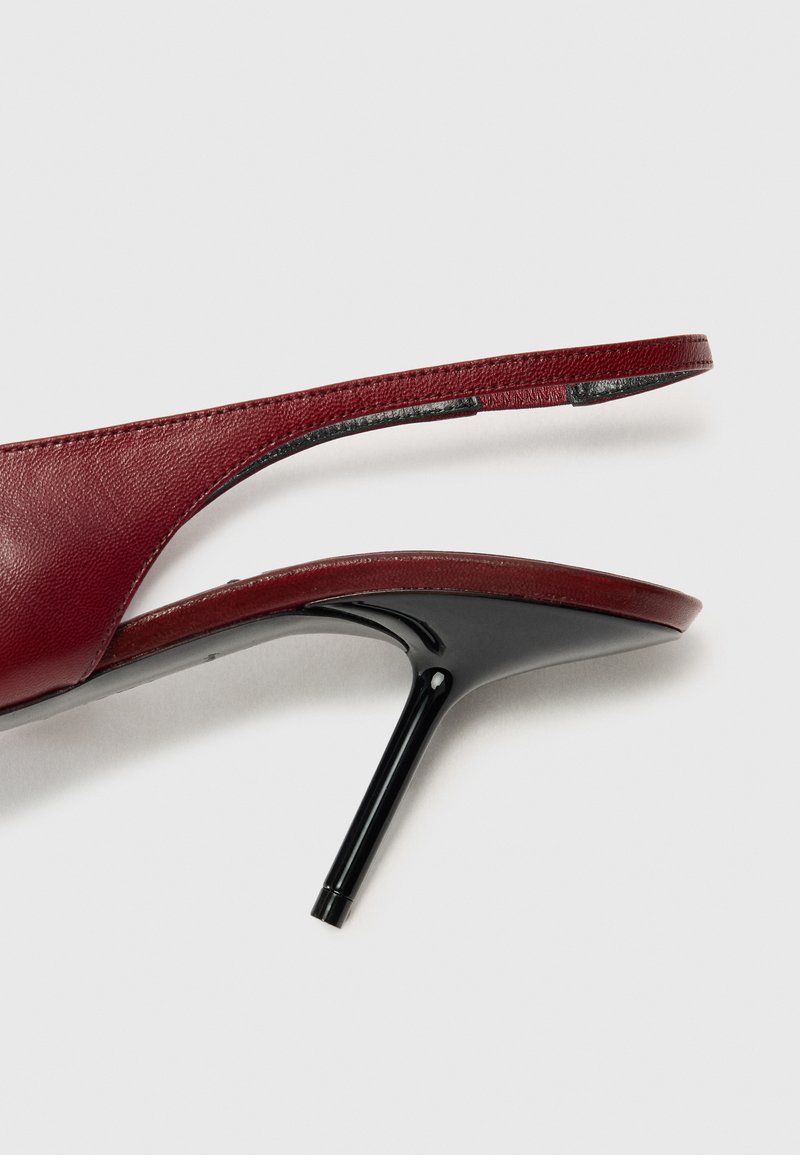 Burgunderfärgade högklackade sandaler med en slank svart stilettklack, mjukt läderövre och öppen baksidesdesign.