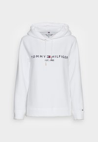 Hvid hættetrøje med frontgrafik "TOMMY HILFIGER EST. 1985" med en flerfarvet logo. Hættetrøjen har snøre i hætten og ribstrikkede manchetter. Blødt stof.