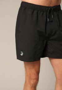 Shorts de bain noirs en tissu léger, dotés d'une ceinture élastique avec cordon de serrage et d'un patch logo sur l'ourlet.