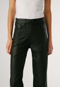 Pantaloni in finta pelle nera con design a gamba dritta, dotati di chiusura con bottone, passanti per cintura e tasche frontali. Texture liscia.