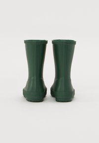 Bottes de pluie en caoutchouc vertes avec une finition lisse et brillante, hauteur jusqu'au mollet, semelles texturées et un bord supérieur à motif festonné.