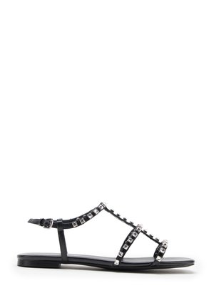 Infradito neri con suola piatta e design a strappo. Presentano dettagli in cristallo lungo le cinghie e una fibbia regolabile per una vestibilità perfetta.