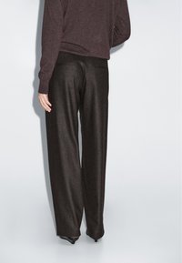 Donker hoge taille broeken met een ontspannen pasvorm, gemaakt van een gestructureerde stof. Voorzien van twee achterzakken en een gladde tailleband.