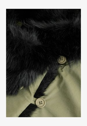 Oliwkowa kurtka z czarnym, sztucznym kołnierzem z futra, z beżowym guzikiem z czterema otworami i gładką tkaniną.