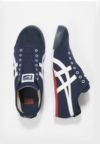 Marina kanvas sneakers med vita ränder, gummisulor och cirkulära snörhål. Har en röd detalj på hälen och en vadderad krage.