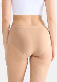 Beige korkeavyötäröiset alushousut, joissa on sileä pinta, pehmeä vyötärönauha ja saumatonta reunaa mukavuutta ja huomaamattomuutta varten vaatteiden alla.