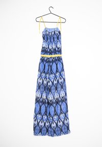 Vestido maxi con patrón geométrico en azul y negro, acentos de tirantes amarillos, corsé con fruncido y tejido ligero. Cuelga de un gancho negro.
