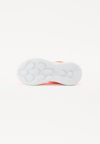 Sole of a shoe featuring white rubber material with a textured grip pattern. Bright orange accents visible along the sides.
