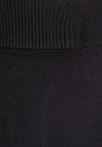 Close-up of black knit fabric showing ribbed texture at top and smooth knit texture below.