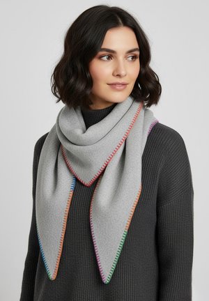 Woman with short dark hair wearing a grey triangular scarf with multicolored stitched edges over a dark ribbed sweater.