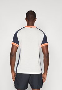 Ανδρικό αθλητικό μπλουζάκι με λευκό πλέγμα στο σώμα, μπλε ναυτικό μανίκια και πορτοκαλί ρίγες στη λαιμόκοψη και στα μανίκια.