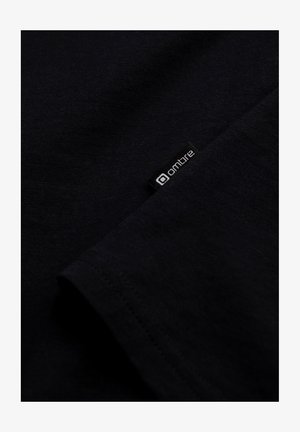 Schwarzes T-Shirt aus weicher Baumwolle, mit glatter Textur und einem kleinen Stoffetikett mit dem "ombre"-Logo am Saum.