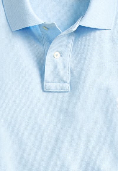 Lyseblå teksturert poloshirt med krage og to hvite knapper på stolp, sentrert i bildet.