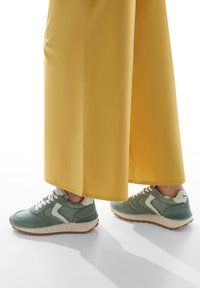 Sneaker verde menta con accenti bianchi, materiali in suede testurizzato e mesh, caratterizzati da una suola marrone a contrasto e branding "VIOLET BLANCHE".