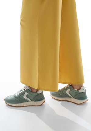 Sneaker verde menta con accenti bianchi, materiali in suede testurizzato e mesh, caratterizzati da una suola marrone a contrasto e branding "VIOLET BLANCHE".