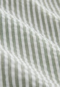 Približek mehke tkanine z navpičnimi zelenimi in belimi ozkimi črtami ter rahlimi gubami, ki ustvarjajo teksturo.