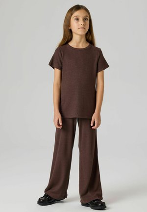 Brun ribstrikket top med korte ærmer kombineret med matchende bukser med vide ben. Outfittet har en afslappet pasform og tekstureret stof. Sorte sko.