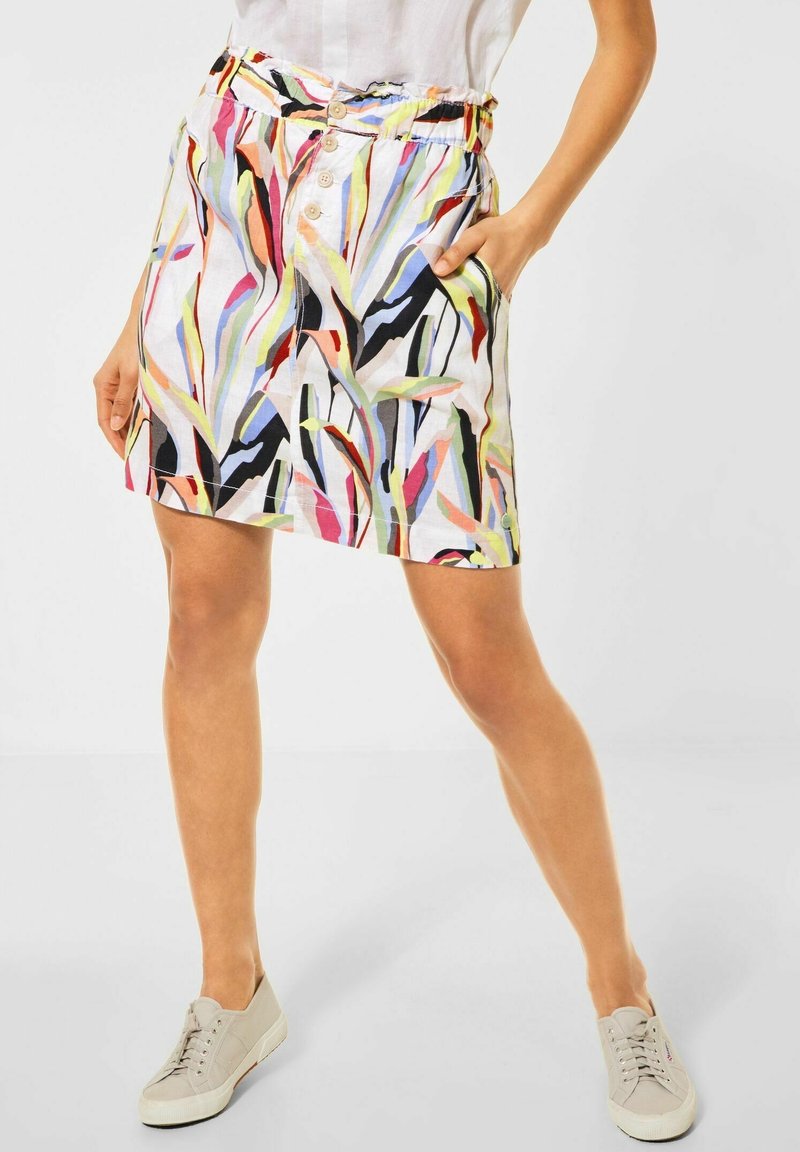 Värikäs kuviollinen hame valkoisella taustalla, jossa on vihreitä, vaaleanpunaisia ja mustia abstrakteja kuvioita, joustava vyötärö ja napituskoristeet.