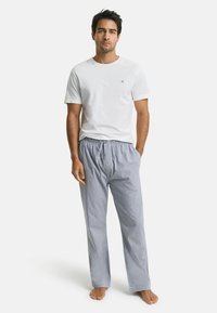 Wit katoenen T-shirt met korte mouwen, gecombineerd met lichtblauwe gestreepte pyjamabroek met een elastische tailleband. Simpel ontwerp, casual pasvorm.