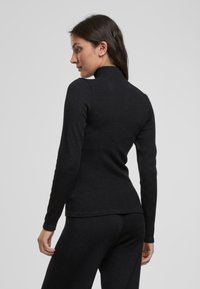 Maglione a collo alto nero con maniche lunghe, vestibilità slim, texture a costine e design con collo alto, realizzato in tessuto morbido.