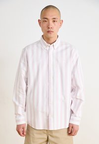 Camisa de botones de rayas rosa claro y blanca, con mangas largas, cuello tipo polo y un logo sutil en el lado izquierdo del pecho. Tela de algodón suave.