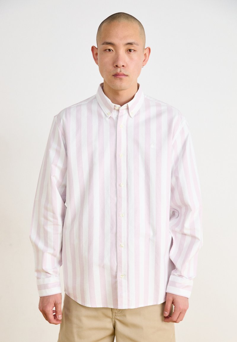 Camisa de botones de rayas rosa claro y blanca, con mangas largas, cuello tipo polo y un logo sutil en el lado izquierdo del pecho. Tela de algodón suave.