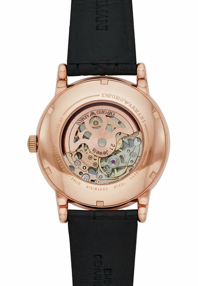 Różowozłoty zegarek Emporio Armani z tylną częścią ukazującą odsłonięty mechanizm automatyczny z 21 kamieniami, czarnym skórzanym paskiem i wygrawerowanymi detalami marki.