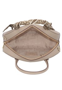 Sac à main beige avec fermeture éclair dorée, poignée enveloppée de tissu, ouverture supérieure montrant une doublure beige imprimée d’un motif répété avec le logo DKNY.