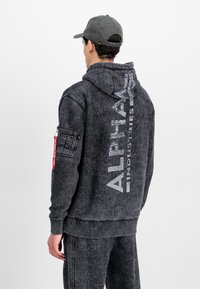 Dark gray hooded sweatshirt with a distressed texture, "ALPHA" branding, and a red zippered pocket detail on the left arm.