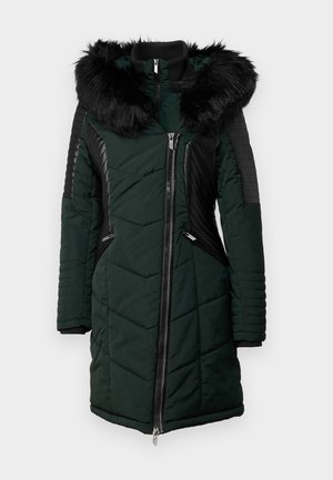 Abrigo acolchado verde con capucha de piel sintética negra, textura acolchada, cremalleras laterales y detalles acanalados negros en las mangas y hombros.