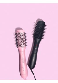 Deux brosses à cheveux : l'une rose et l'autre noire. Les deux présentent des réglages de chaleur, des poils arrondis et des poignées ergonomiques, posées sur un fond rose.