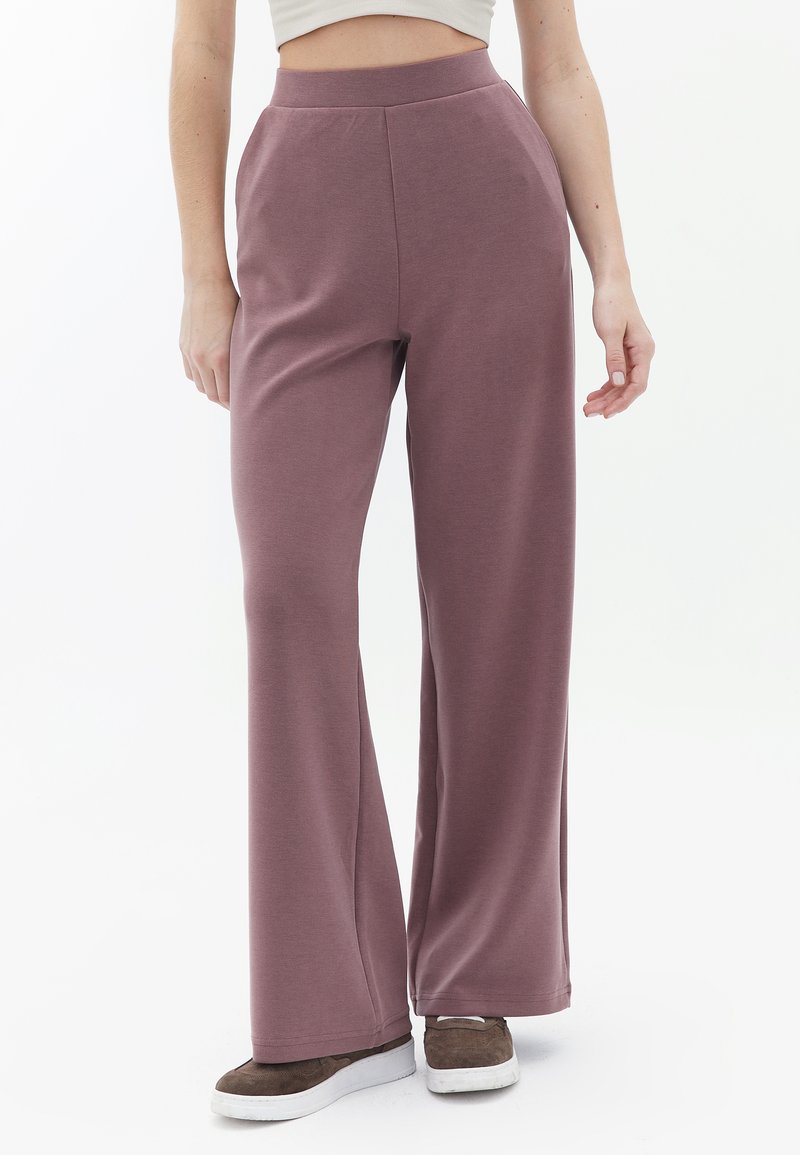 Lila weite Hosen aus weichem Stretchstoff mit hohem Bund und glatter Textur, kombiniert mit braunen Schuhen.