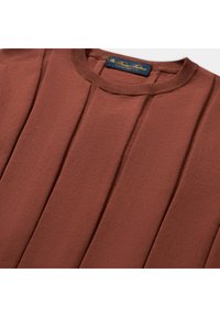 Svetr v rezavé barvě s žebrovaným kulatým výstřihem a skládáním. Měkká textura a pletená látka, označená modro-zlatou značkovou štítkem.