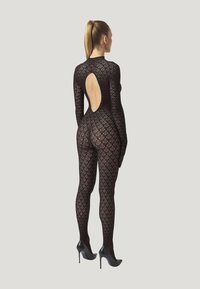 Zwart kanten bodysuit met een diamanten patroon, aansluitend ontwerp, lange mouwen en een diepe ruguitsnijding, gedragen met zwarte hoge hakken.