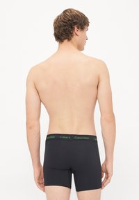 Zwarte boxershorts met een groene Calvin Klein-logo tailleband, met een zachte, gladde textuur en een aansluitend ontwerp.