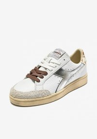 Sneaker in pelle bianca con punta in suede grigia, dettagli in argento e lacci marroni. Presenta un pannello posteriore testurizzato e un design perforato sui lati.