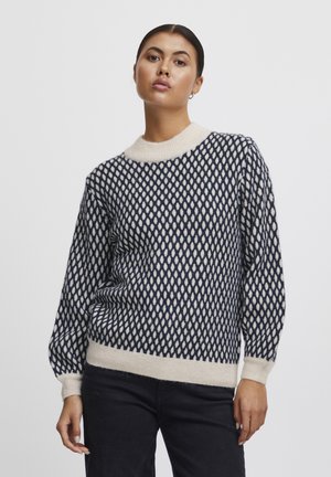 Strikket sweater i marineblå og creme med diamantmønster, ribbet rund hals og manchetter. Blød tekstur og løs pasform.