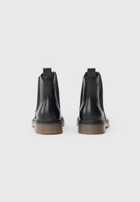 Bottines en cuir noir avec une finition lisse, des panneaux latéraux élastiques et des semelles en caoutchouc marron. Comprend une languette à l'arrière pour un enfilage facile.