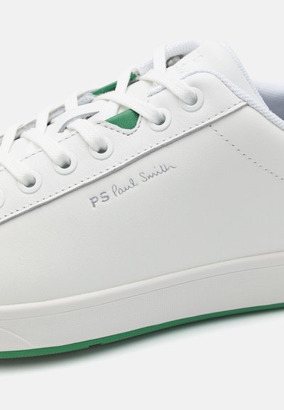 Fehér bőr sportcipő zöld részletekkel, lapos fűzőkkel, dombornyomott "PS Paul Smith" logóval és texturált gumitalppal.