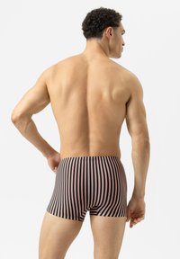 Mustat ja vaaleanpunaiset raidalliset bokserit, joissa on istuva muotoilu ja joustava vyötärö, jossa on pystysuorat viivat ja sileä kankaan rakenne.