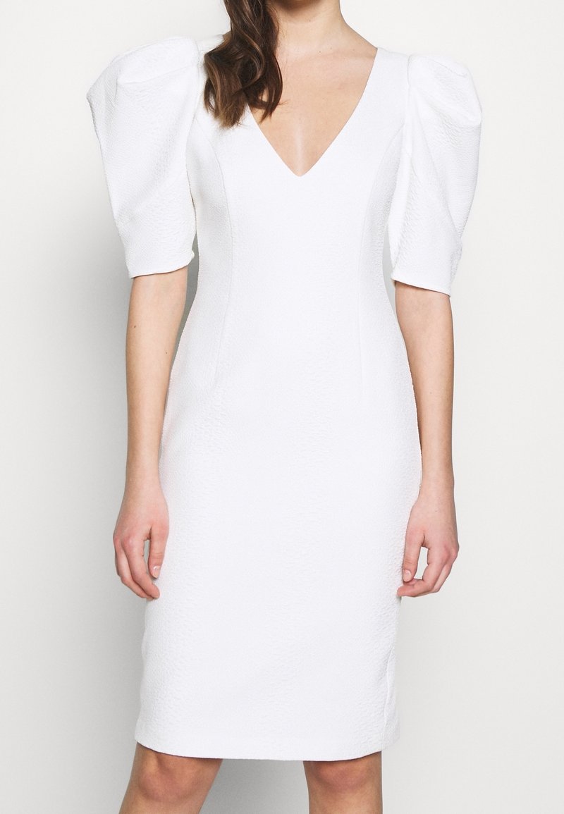 Biała sukienka do kolan z dekoltem w kształcie litery V i teksturowanym materiałem. Posiada krótkie, bufiaste rękawy oraz dopasowany krój.