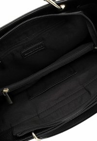 Interno della borsa nera con rivestimento in tessuto liscio, dotato di una tasca con zip e una tasca a scomparsa per l'organizzazione. Accessori in tonalità oro.