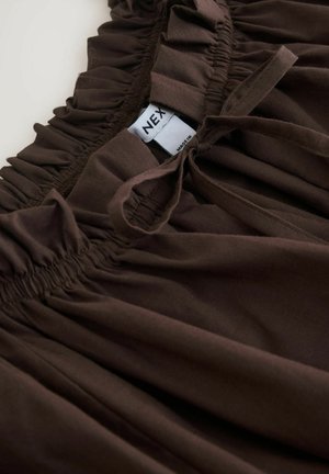 Brauner Stoff mit geraffter Rüschendetail, ausgestattet mit einem genähten elastischen Bund. Enthält ein Etikett mit "NEX". Glatte Textur und einfarbig.