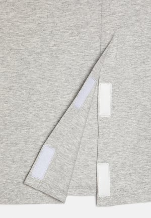 T-shirt en coton gris avec un ourlet incurvé, des accents en Velcro blanc visibles et un tissu doux et texturé.