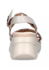 Sandalia beige con un tacón ancho, correa ajustable en el tobillo, diseño cortado en la parte superior y suela de textura suave.
