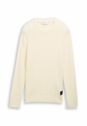 Kremo spalvos giliu raštu megztinis su ilgomis rankovėmis, apvaliu iškirpimu ir juodu akcentiniu žymeniu šone. Minkšta tekstūra ir laisvas pjūvis.