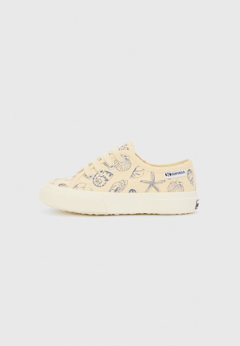 Canvas sneakers in pale yellow with navy shell and starfish pattern. Rounded toe, lace-up front, textured rubber sole. Logo on side.