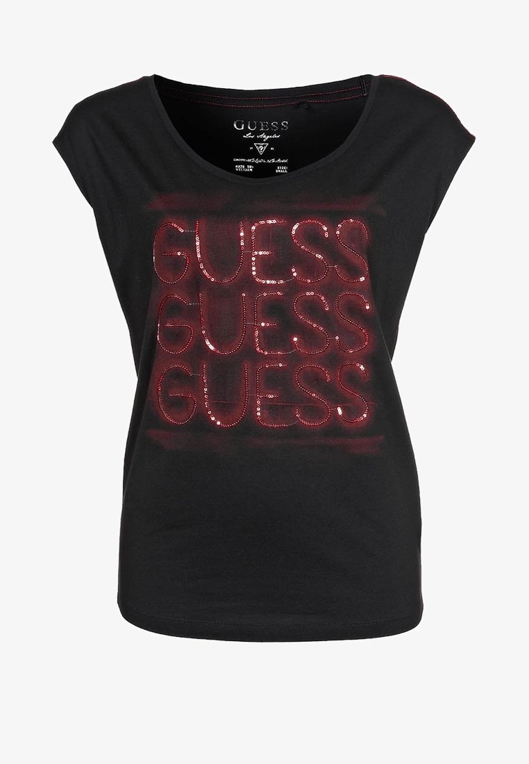Sort kortærmet t-shirt med skinnende røde palietter, der stavrer "GUESS" flere gange. Blødt stof, rund halsudskæring og afslappet pasform.