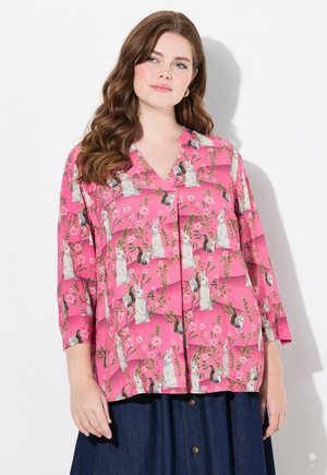 Pink shirt with a floral and rabbit pattern, featuring a V-neck and three-quarter sleeves. Made from a light, smooth fabric.